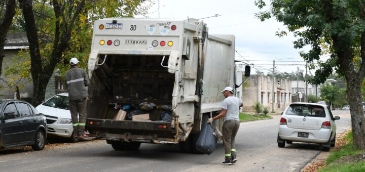 alt="Dos operarios municipales en la parte trasera de un camión Econovo realizando la recolección de residuos en Concordia"