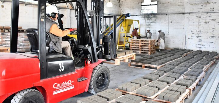 alt="Un montacargas rojo traslada pallets de bloques de cemento secados en la planta municipal de adoquines de Concordia"