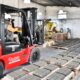 alt="Un montacargas rojo traslada pallets de bloques de cemento secados en la planta municipal de adoquines de Concordia"
