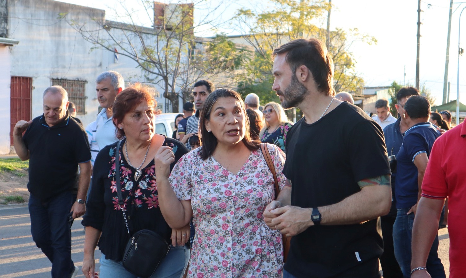 alt="el intendente Francisco Azcué dialoga con dos vecinas de Concordia durante una recorrida por los barrios. Detrás de ellos se observa a gente participando de la caminata del presidente municipal"