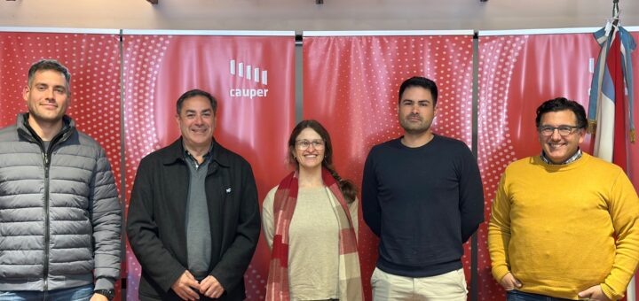 alt="Cinco profesionales de Codesal y el Colegio de Arquitectos de pie frente a banners institucionales rojos, tras acordar la planificación de proyectos para el lago Salto Grande"