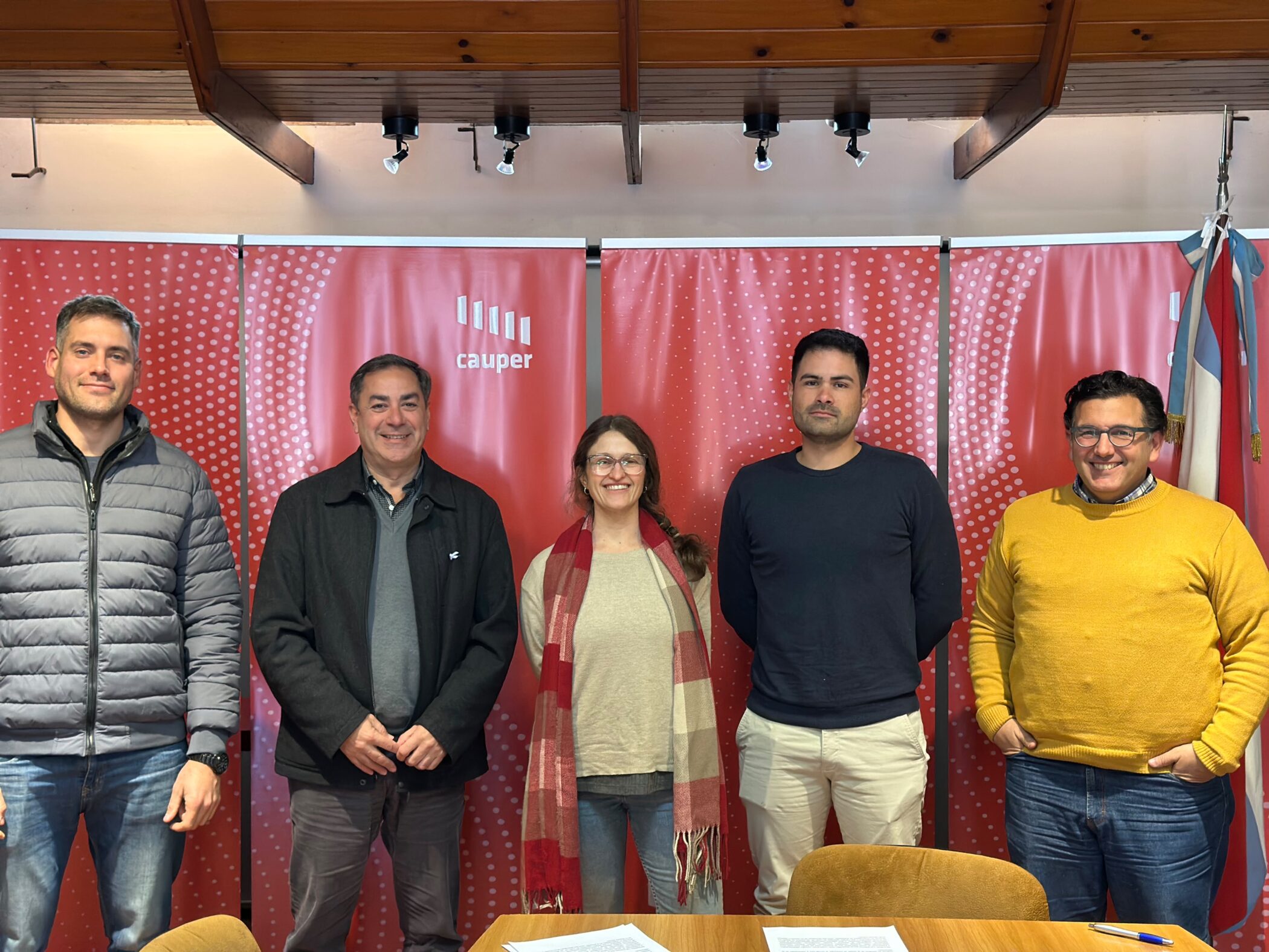 alt="Cinco profesionales de Codesal y el Colegio de Arquitectos de pie frente a banners institucionales rojos, tras acordar la planificación de proyectos para el lago Salto Grande"