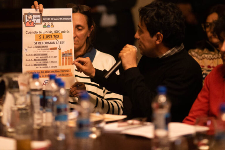 alt="Dirigente de AGMER muestra una infografía sobre el impacto de la reforma previsional"