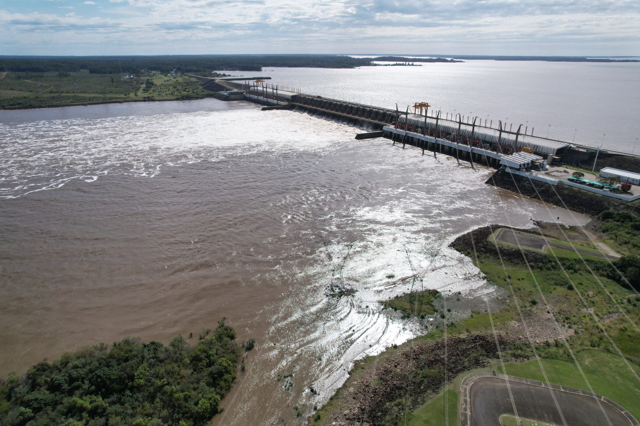 alt="Vista aérea del complejo de Salto Grande con alta turbulencia en vertederos, alertando sobre la crecida del Río Uruguay por El Niño"