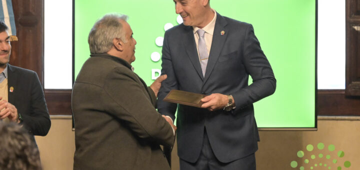 alt="Marcelo Spinelli sosteniendo la plaqueta en el homenaje a cooperativas entrerrianas"