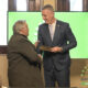 alt="Marcelo Spinelli sosteniendo la plaqueta en el homenaje a cooperativas entrerrianas"