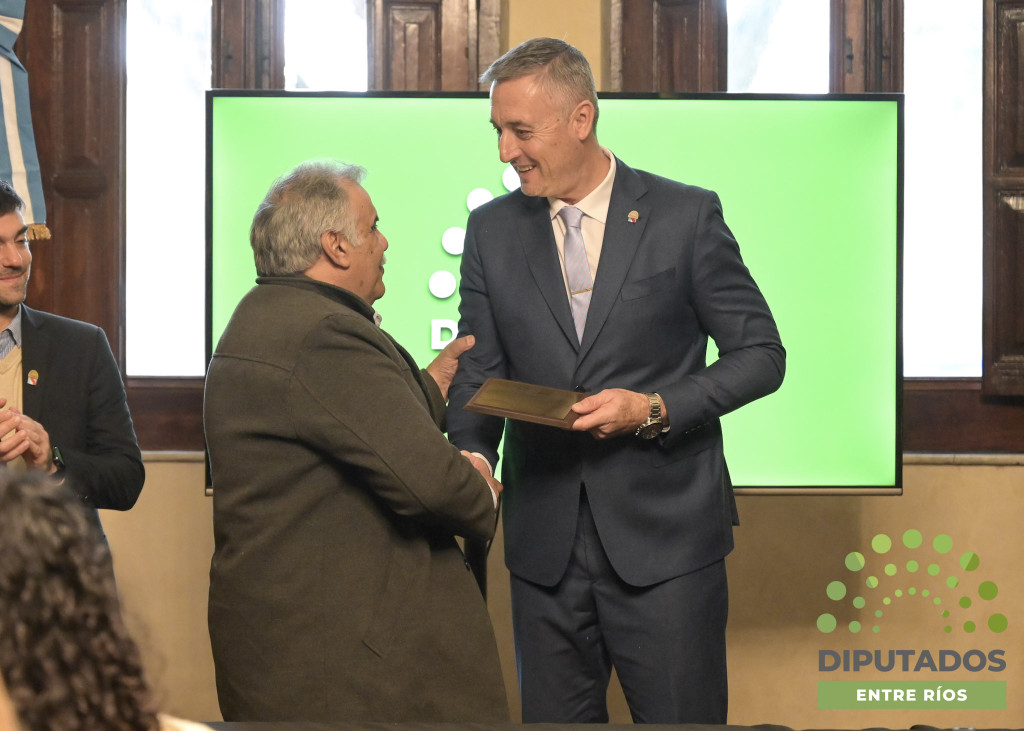 alt="Marcelo Spinelli sosteniendo la plaqueta en el homenaje a cooperativas entrerrianas"