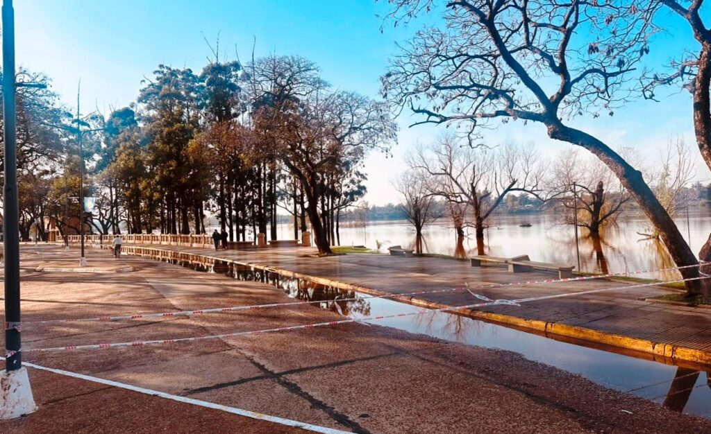 alt="ante la creciente, el agua del río Uruguay comienza a invadir el pavimento de la costanera sur de Concordia mientras cintas de seguridad cierran el paso vehicular"