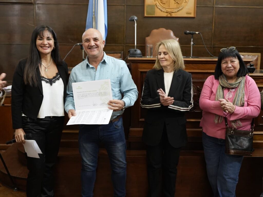 alt="2.	Marcelo Coutinho Villalba sostiene el certificado de reconocimiento por las 1000 emisiones de Paralelo 31 junto a la viceintendente Magdalena Reta de Urquiza y la concejal Villalba"