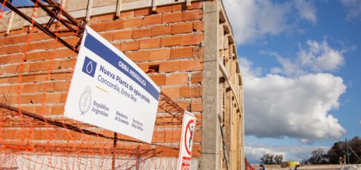 alt="Cartel de la obra de agua potable de Concordia frente al edificio de la nueva planta potabilizadora en construcción"