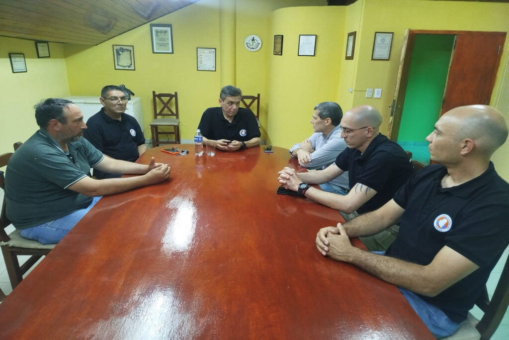 alt="Seis integrantes de Defensa Civil y organismos locales reunidos alrededor de una mesa de madera, en una sala de paredes amarillas, durante una reunión de prevención ante El Niño en Entre Ríos"