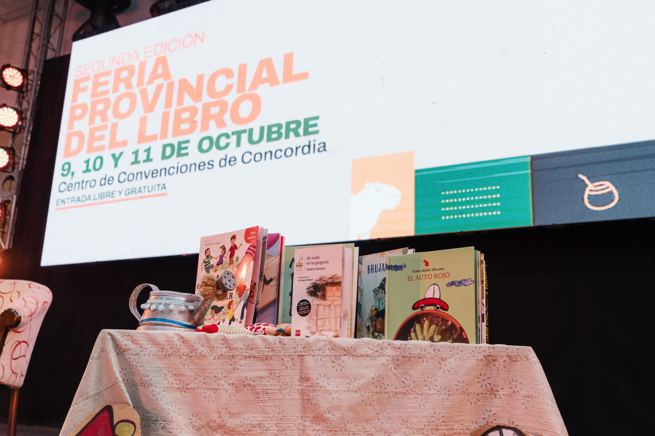 alt="Libros exhibidos bajo la pantalla de la Feria Provincial del Libro en Concordia, segunda edición, 9, 10 y 11 de octubre"