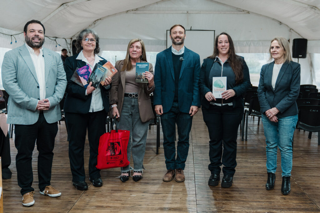 alt="Seis personas posan con libros en una carpa de la Feria Provincial del Libro en Concordia"