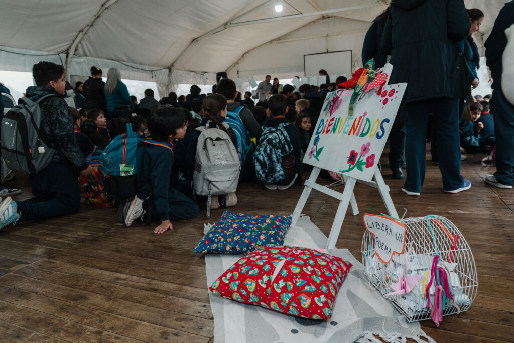 alt="Niños y niñas sentados en una carpa junto a un cartel de bienvenida en la Feria Provincial del Libro en Concordia"