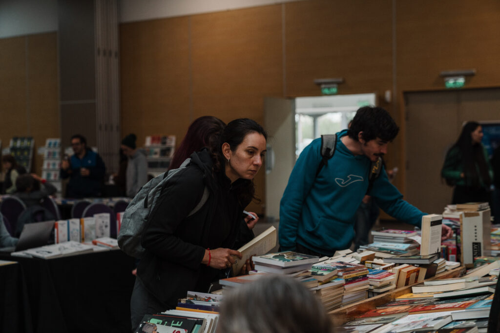 alt="Dos visitantes miran pilas de libros en una mesa de la Feria Provincial del Libro en Concordia"