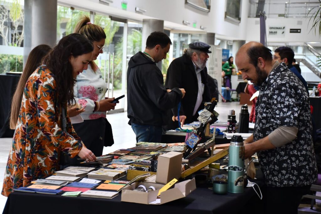 alt="Visitantes observan libros y ediciones artesanales en un stand de la Feria Provincial del Libro en Concordia"