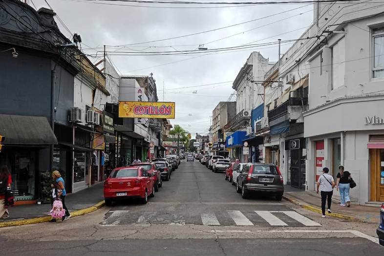 alt="Calle comercial con autos estacionados, escena asociada al estacionamiento medido liberado en Concordia"