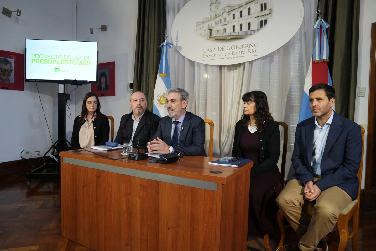 Ministro y funcionarios presentan el presupuesto provincial 2027 en un salón con las banderas de Entre Ríos y de Argentina.