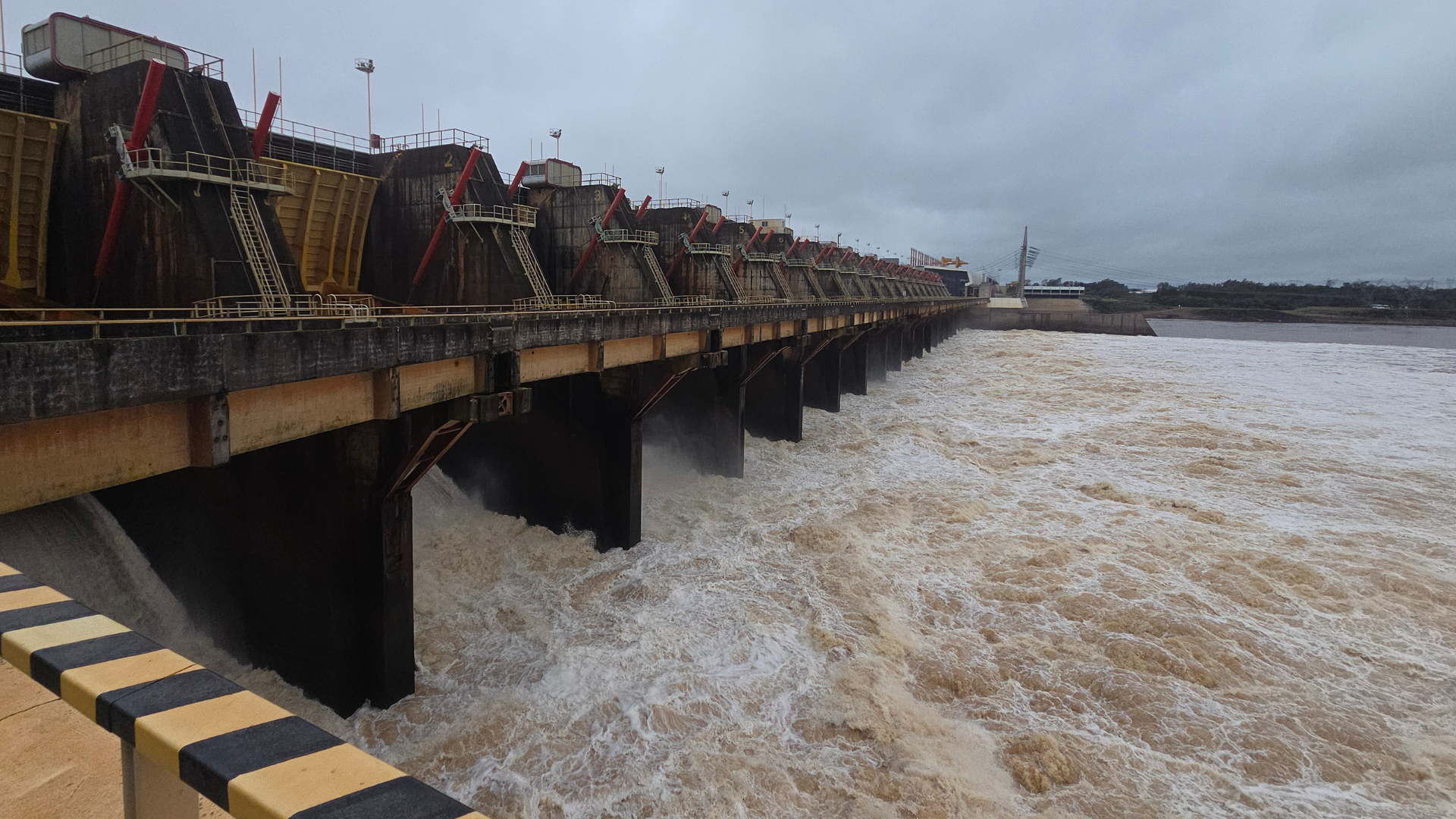 alt="Vertedero de la represa de Salto Grande abierto durante la crecida del río Uruguay en Concordia y Salto el 26 de octubre de 2026, con gran caudal de agua marrón"